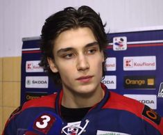 a young man in a hockey uniform talking to the media