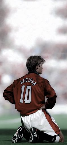 a soccer player sitting on the ground with his back to the camera and looking down