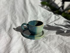 a cup and saucer sitting on top of a white sheet