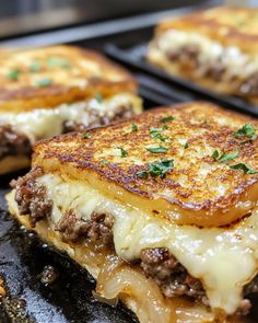 three cheeseburger sandwiches sitting on top of a grill