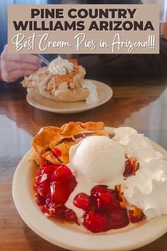 a white plate topped with pie and ice cream on top of a wooden table next to another plate