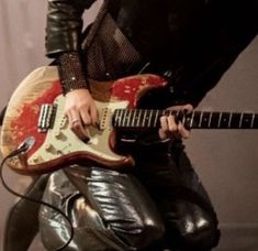 a man in leather pants holding an electric guitar