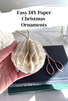 a hand holding a paper ornament on top of a table next to some books