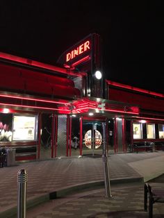 the diner is lit up at night with red lights