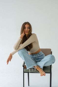 a woman sitting on top of a chair with her legs crossed and looking at the camera