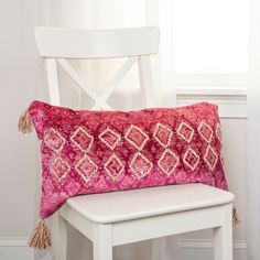 a white chair with a pink pillow on it