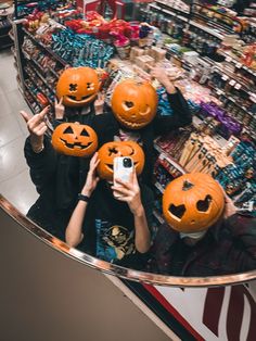 three people holding pumpkins in front of their faces while taking a selfie at a store