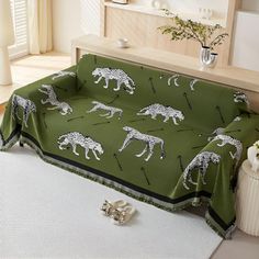 a living room with a couch covered in a green blanket and white giraffes on it