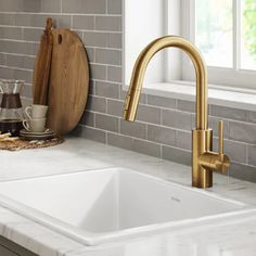 a white kitchen sink sitting under a window next to a cutting board and utensils