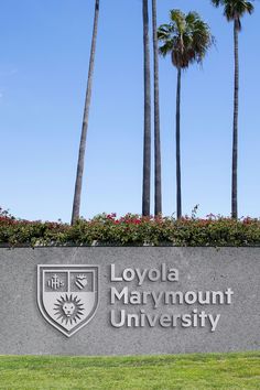 the sign for loyola marymount university in front of palm trees and flowers