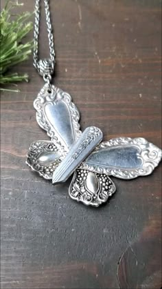 a silver butterfly necklace sitting on top of a wooden table