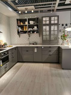 a large kitchen with gray cabinets and white counter tops, along with wooden flooring