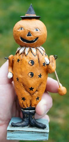 a hand holding a small wooden toy with an evil face on it's head