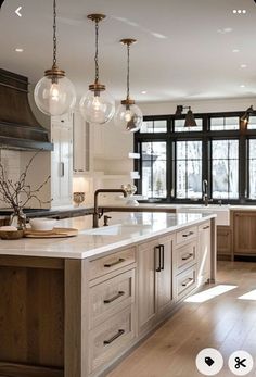 a large kitchen with an island in the middle and lots of lights hanging from the ceiling