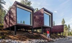 two people are standing on the steps leading up to some very unusual houses in the woods