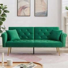 a living room with a green couch and two paintings on the wall above it, along with a coffee table