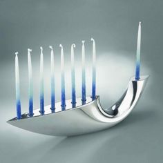 a silver menorah with blue candles on it's side, in front of a gray background