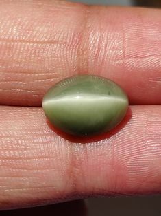 a close up of a person's hand holding a green stone