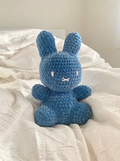 a blue crocheted bunny sitting on top of a bed