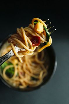 a fork full of pasta with sauce and vegetables