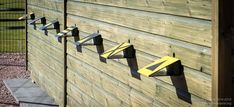 there is a wooden fence that has five metal arrows on it and three are painted yellow