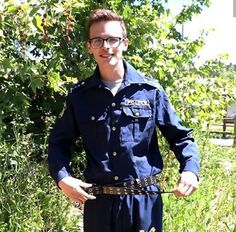 a man in blue uniform holding onto a metal chain with trees behind him and bushes to the side