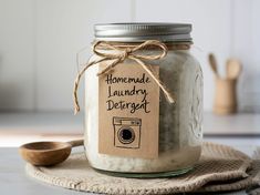 a glass jar filled with laundry deter sitting on top of a table next to a wooden spoon