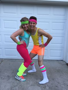 two people are posing in front of a garage door with their arms around each other