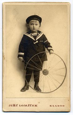 an old photo of a young boy holding a wheel