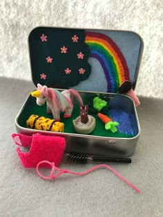 an open tin box with toys in it and a pink string hanging from the side