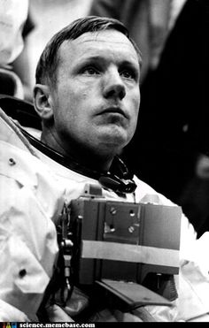 black and white photograph of man in space suit with camera strapped to his chest looking up