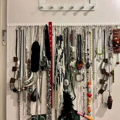 there are many necklaces hanging on the wall and in front of it is a purse