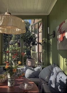 a room with green walls and lots of pillows on the couches in front of an open window