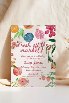 a card that says fresh off the market next to some flowers and fruit on a bed