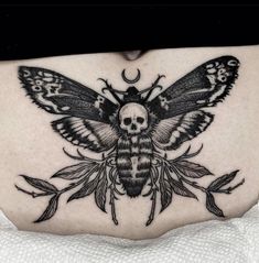 a woman's stomach with a black and white moth tattoo on the side of her belly