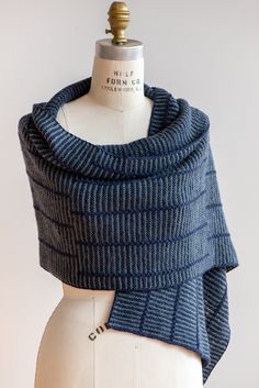 a white mannequin wearing a blue and black striped knitted scarf on top of a dummy