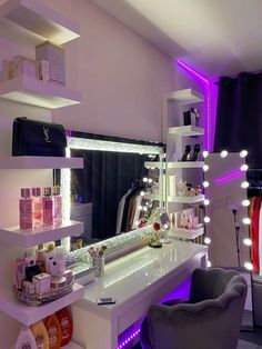 a white vanity with lights on it and a chair in front of the mirror that is lit up