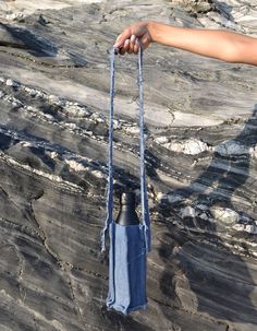 a hand holding a blue bag on top of a rock