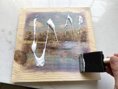 someone is using a brush to paint the image on wood with white acrylic