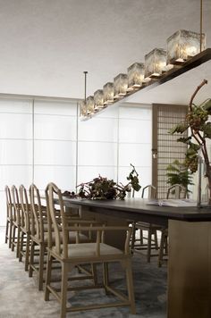 a dining room table and chairs with candles on the shelves above it, along with plants in vases