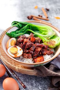 a bowl filled with rice, meat and vegetables next to eggs on top of a table