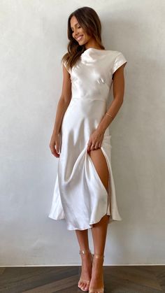 a woman in a white dress posing for the camera with her legs slited up