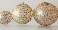 three white ornaments sitting next to each other on top of a table with gold foil covering them