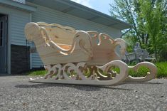 a wooden sleigh sitting on the ground in front of a house