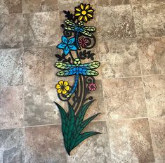 a decorative metal wall hanging with flowers and dragonflys on it's side