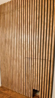 a room with wooden slats on the wall and wood flooring in front of it