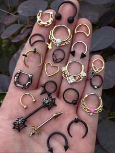 a person is holding many different types of rings and piercings in their hand,