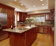 a large kitchen with wooden cabinets and stainless steel appliances in the center, along with hardwood flooring