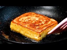 a square piece of food cooking in a frying pan