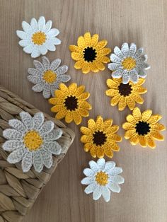 several crocheted flowers sitting on top of a wooden table next to a basket